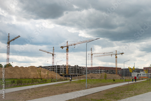 Construction cranes near the unfinished buildings. Construction and developing new districts © linagaga