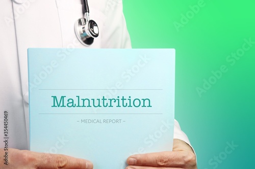 Malnutrition. Doctor (male) with stethoscope holds medical report in his hands. Cutout. Green turquoise background. Text is on the documents. Healthcare/Medicine photo