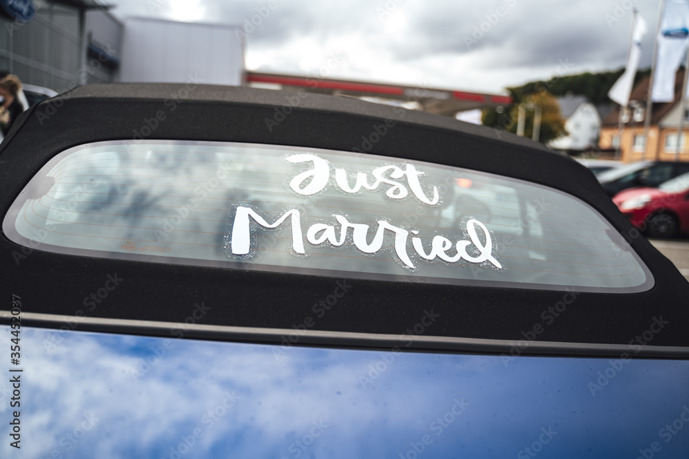 Obraz premium Just married white inscription on rear window of blue cabriolet car with black convertible roof. Wedding day concept.