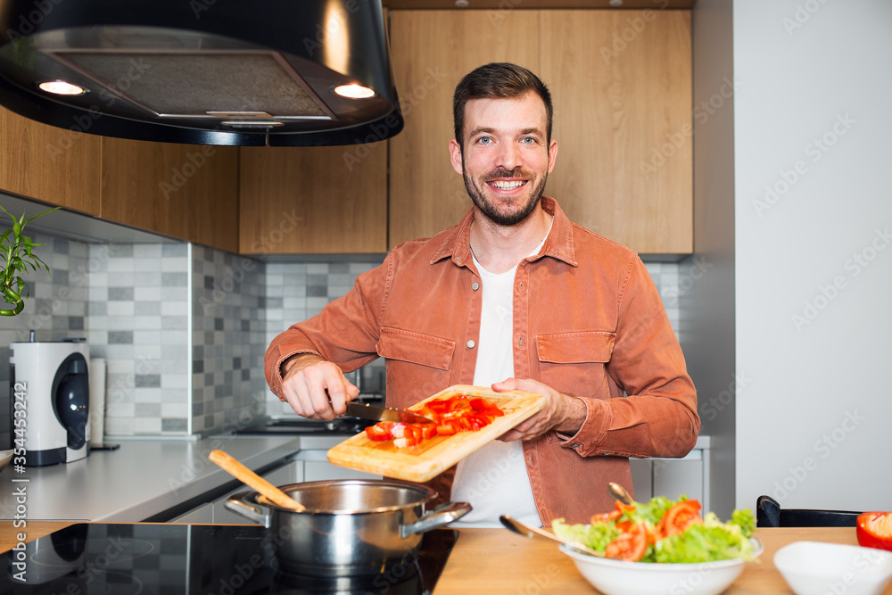 Handsome young man cooking in kitchen