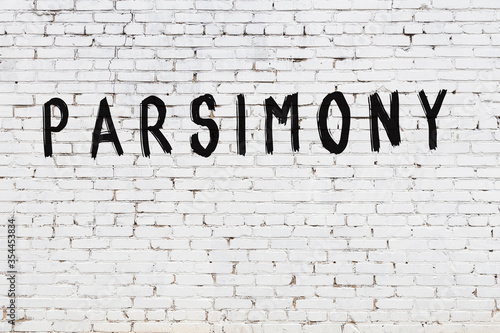 White wall with black paint inscription parsimony on it