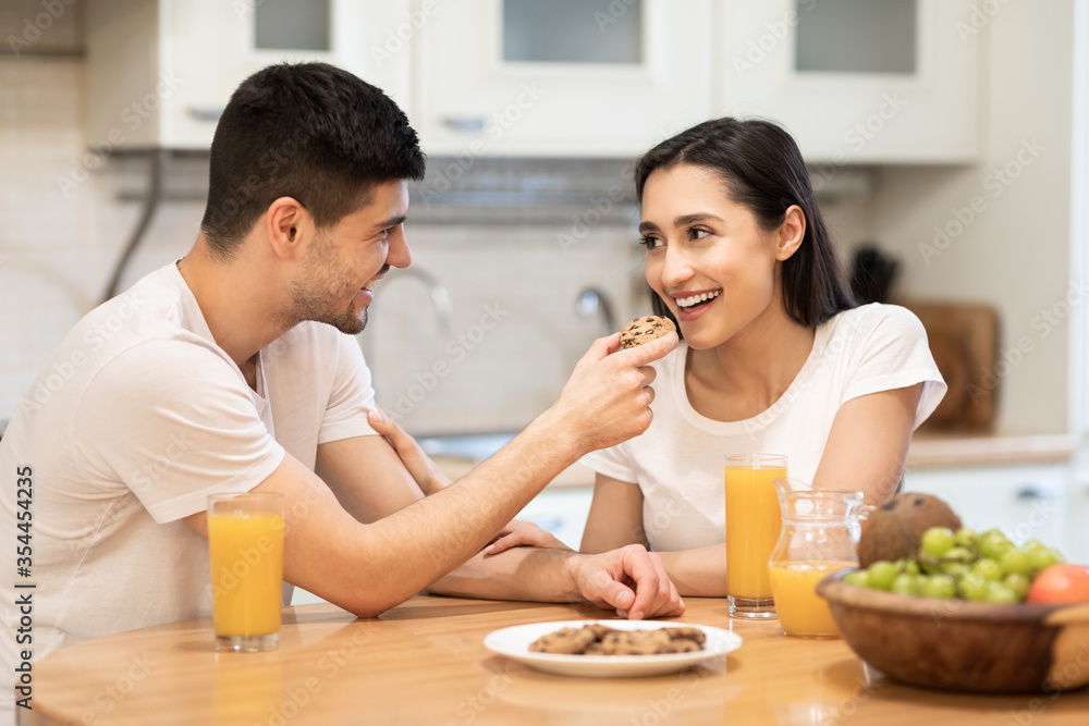 Smiling guy feeding his girl, couple having breakfast together