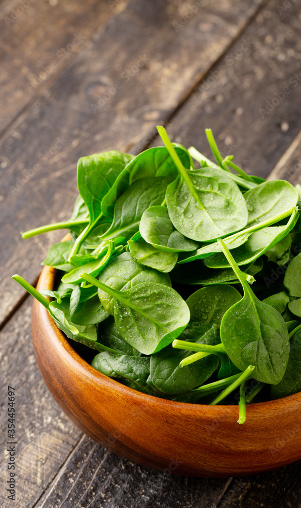 Close-up view of Spinach leafs in Wooden Bowl on wooden background with copy space Close-up view of Spinach leafs in Wooden Bowl on wooden background with copy space