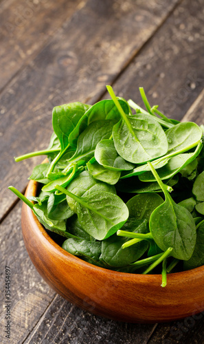 Close-up view of Spinach leafs in Wooden Bowl on wooden background with copy space