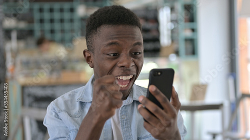 Portrait of Young African Man Celebrating Success on Smartphone