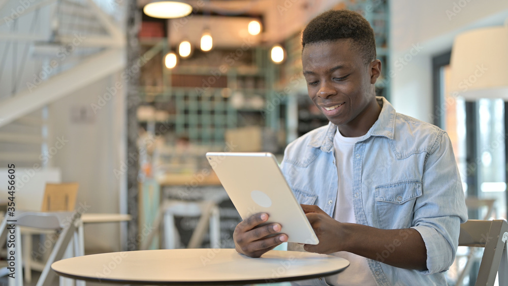 Fototapeta premium Cheerful Young African Man Using Tablet in Cafe