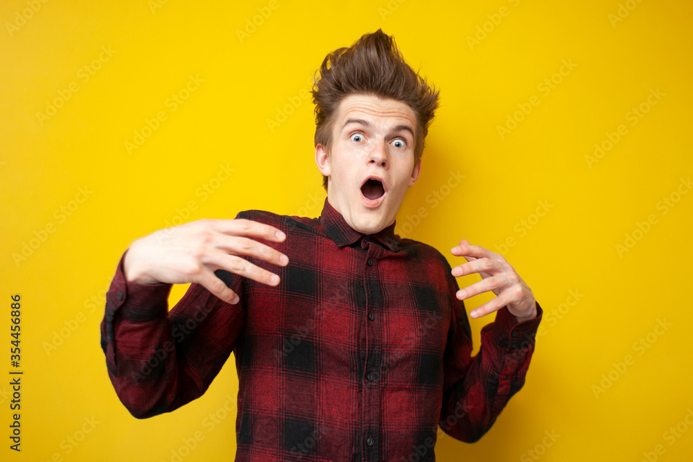 scared guy is surprised and screaming on yellow isolated background, shocked man in stress