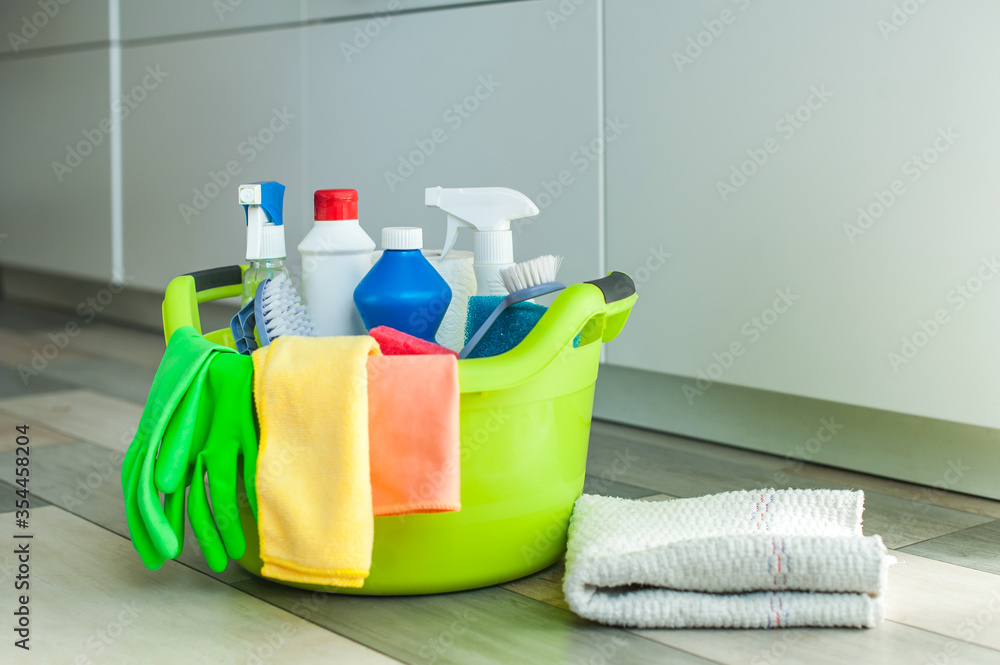 A set of cleaning products on the floor in a basin, next to a rag for the floor. A set of cleaning products on the floor in a basin, next to a rag for the floor.