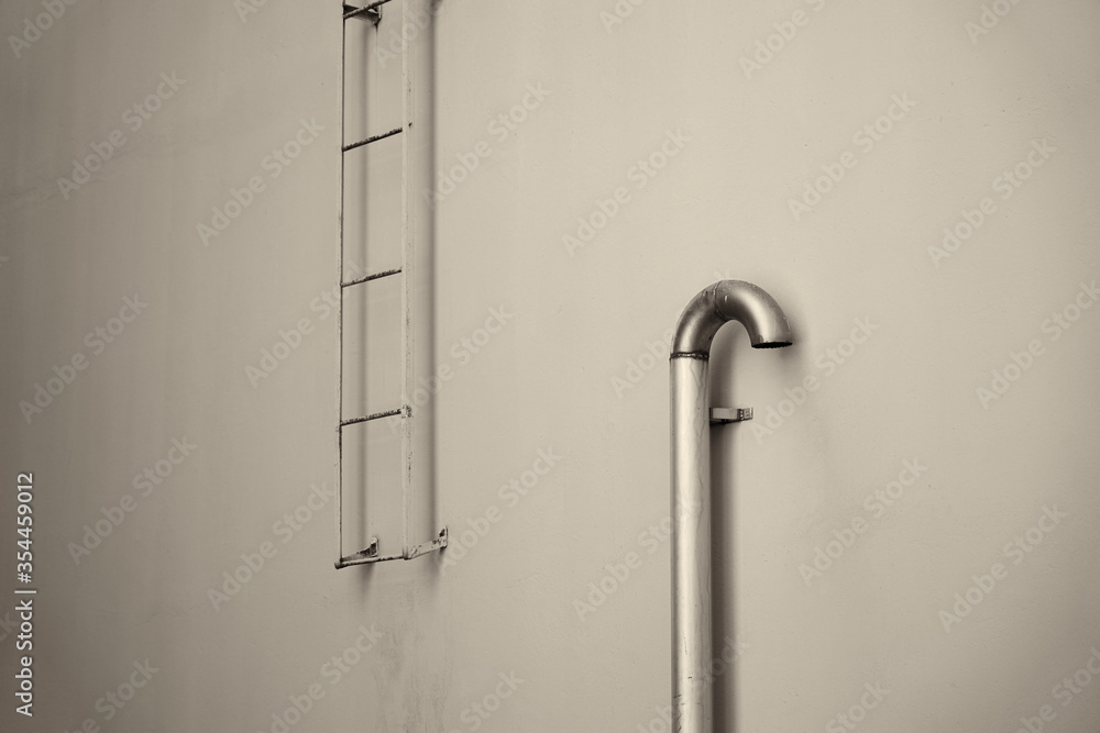 A fire stairs outdoors on a wall. Fire escape and ventilation pipe. A fire stairs outdoors on a wall. Fire escape and ventilation pipe.