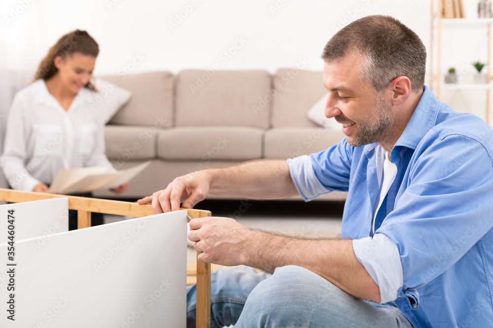 Obraz premium Happy Couple Assembling Furniture Kit Together Making Renovation Sitting Indoors