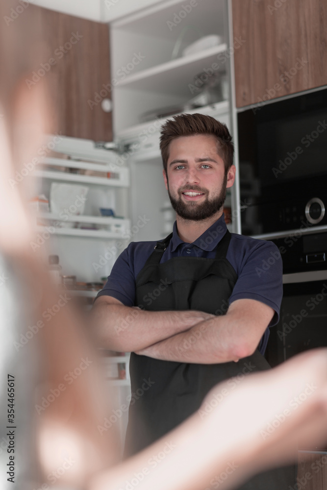 Smiling attractive young man standing near refrigerator Smiling attractive young man standing near refrigerator