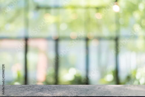 Abstract bokeh sunlight and tree background of nature in green color with Steel black table.