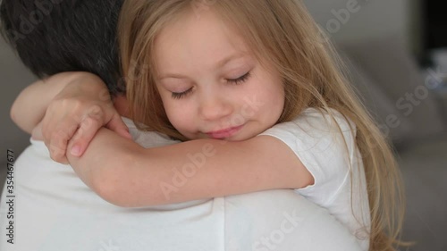 Father's Portrait of father holding child girl in his hands and hugging at home. Dad cuddling and kissing with his daughter. Father's day. little girl blue eyes and blonde hair hugs dad close up
