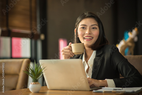 Smiling Businesswoman Drinking Coffee At Desk 
