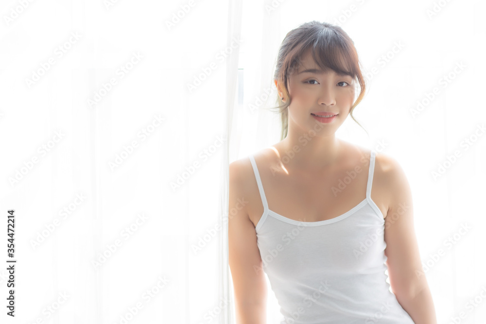 Portrait of beautiful young asian woman standing the window and smile while wake up with sunrise at morning, girl happy with freshness and cheerful, lifestyle and relax concept. Portrait of beautiful young asian woman standing the window and smile while wake up with sunrise at morning, girl happy with freshness and cheerful, lifestyle and relax concept.
