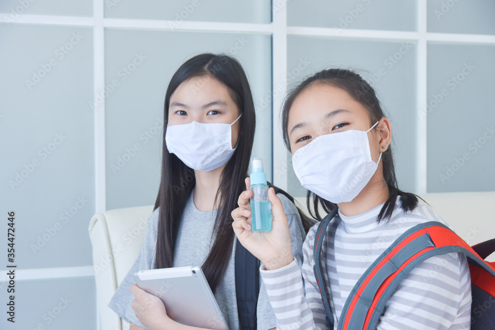 Young asian schoolgirls wearing facial mask and using alcohol spray at school for prevention covid-19 infection.