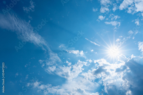 blue sky with clouds and sun shines with sunbeams in the day