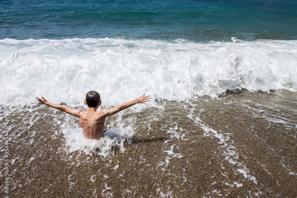 Fototapeta premium Niño disfrutando en una playa, mar y arena