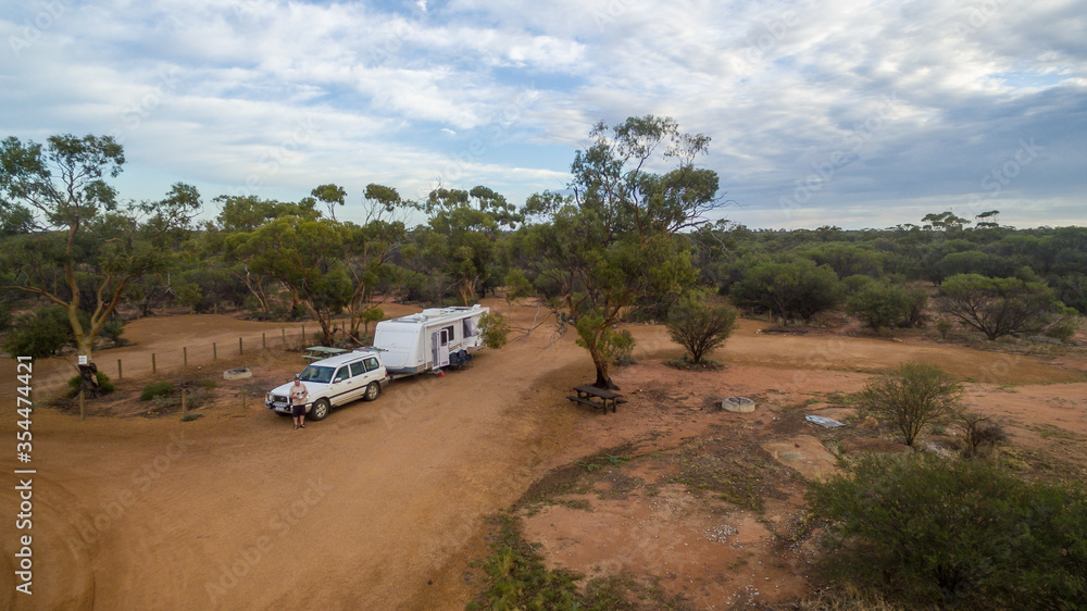 Low level drone view of a 4WD and a caravan in the Australian outback.