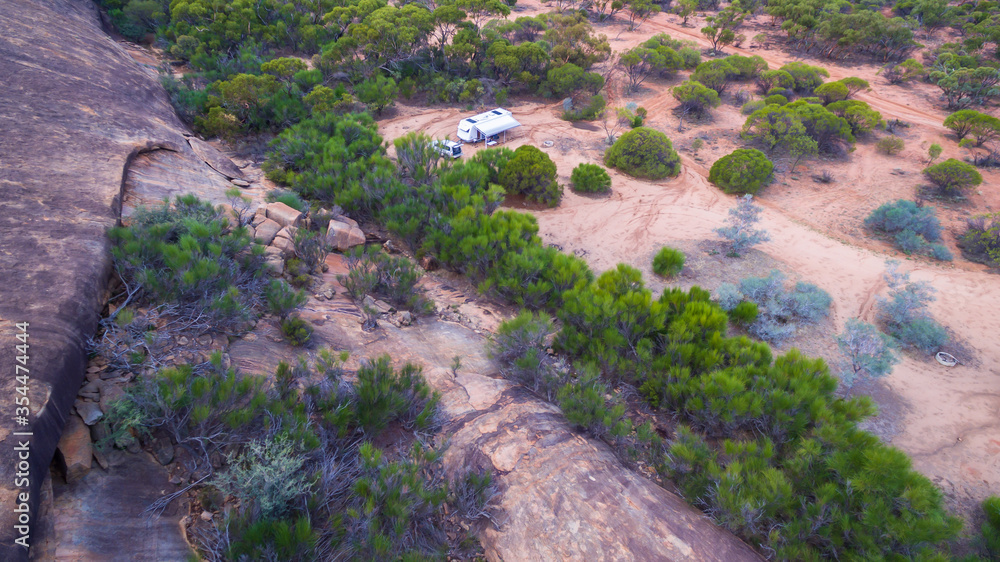 Oblique drone view of a 4WD and a caravan in at a free camp near a granite outcrop in the Australian outback. Oblique drone view of a 4WD and a caravan in at a free camp near a granite outcrop in the Australian outback.