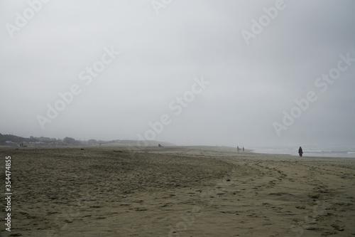 Deserted beach. People in the distance. Fog on the shore