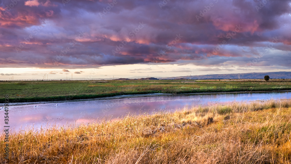 Dramatic sunset landscape with storm clouds reflected in the restored wetlands of South San Francisco Bay Area; Mountain View, California
