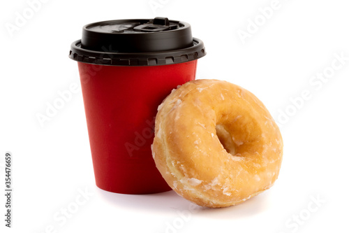 a sugar glazed donut resting against a red takeout coffee cup isolated on white
