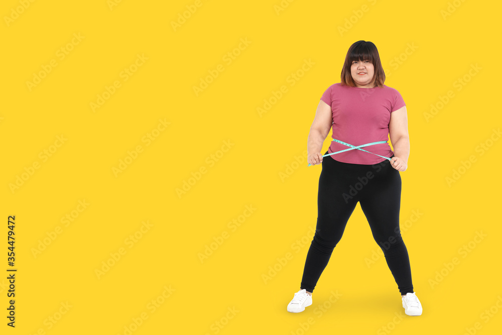 Fat Asian women exercise to lose weight, use a waist tape to check their shape. Health care concept. Yellow background. Clipping Path. isolated