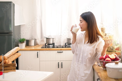 Young Asian woman in the kitchen drinking milk for breakfast, Healthy food concept