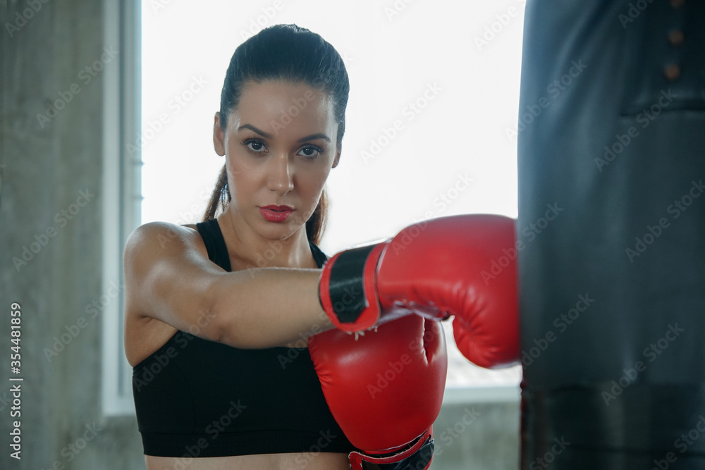 Young attractive Caucasian woman punching a bag with red Boxing Gloves. Beautiful female Boxer Training