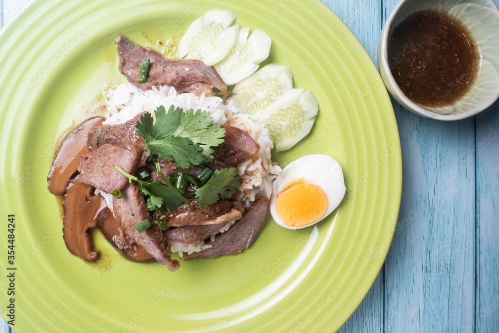 Thai food. Roasted pork on rice With boiled eggs and cucumbers on a rice dish. Placed on a wooden floor.