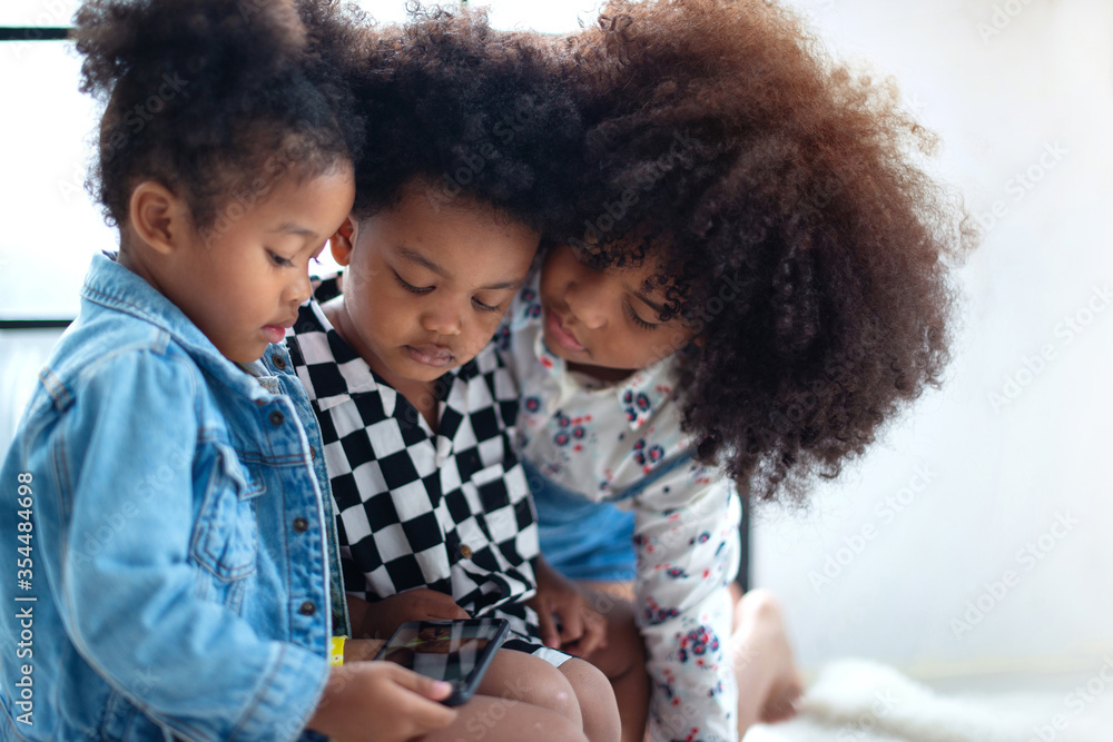 Three Dark skinned children watching using smartphone, watch social media video app, look at mobile screen at home. Three Dark skinned children watching using smartphone, watch social media video app, look at mobile screen at home.