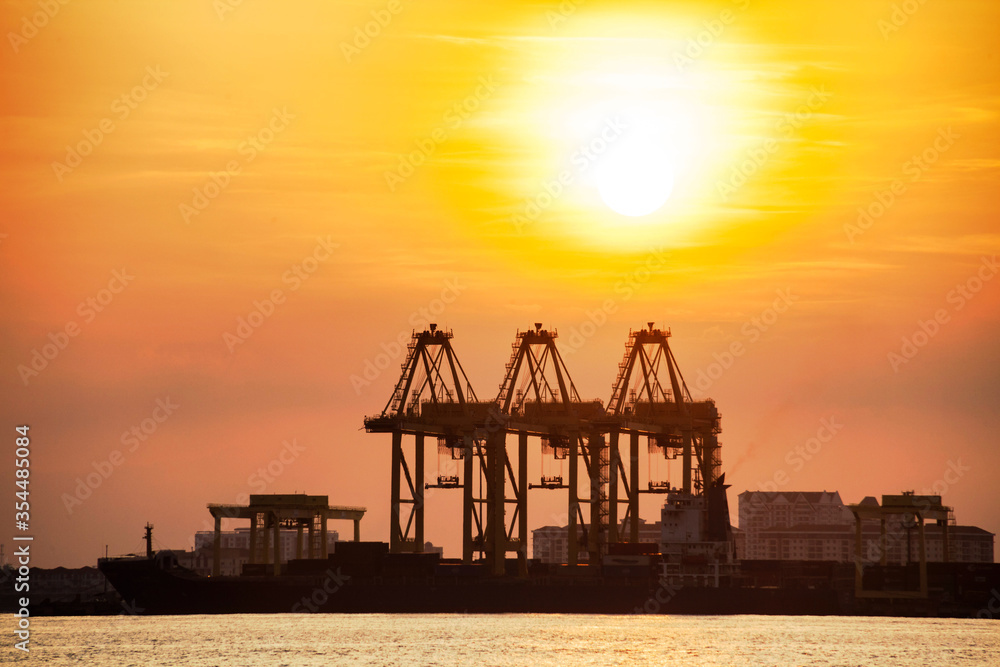 Crane for shipping container carrier with sunrise background
