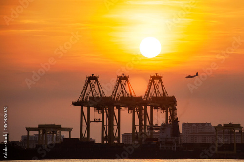 Crane for shipping container carrier with sunrise background 