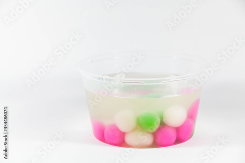 Colorful glutinous rice ball in a transparent plastic container in a white isolated background