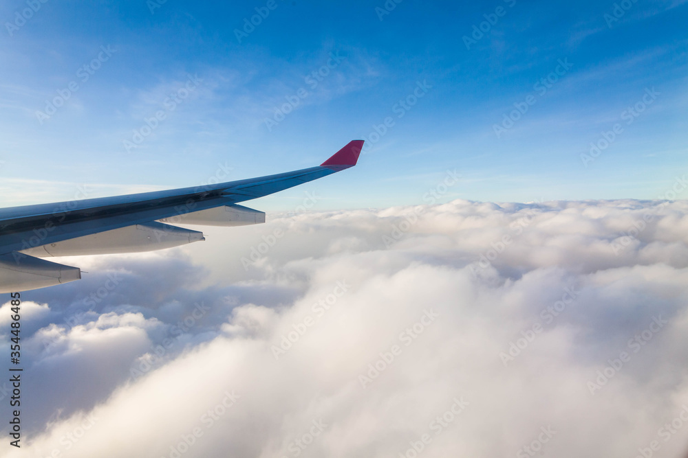 Plane wing view from inside plane in midair with blue sky cloud background Plane wing view from inside plane in midair with blue sky cloud background