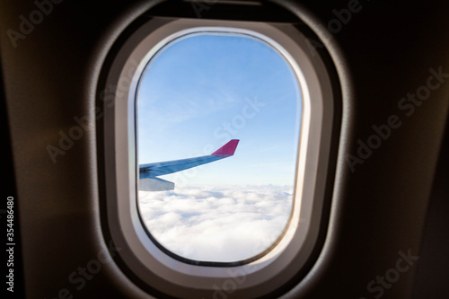Plane wing view from inside plane in midair with blue sky cloud background