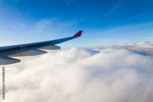 Plane wing view from inside plane in midair with blue sky cloud background © keongdagreat