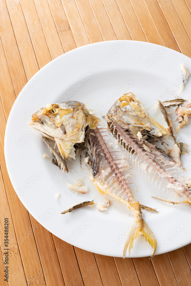 Thai style fermented fish in plastic container style fried mackerel on plate ate and left on wooden background Thai style fermented fish in plastic container style fried mackerel on plate ate and left on wooden background