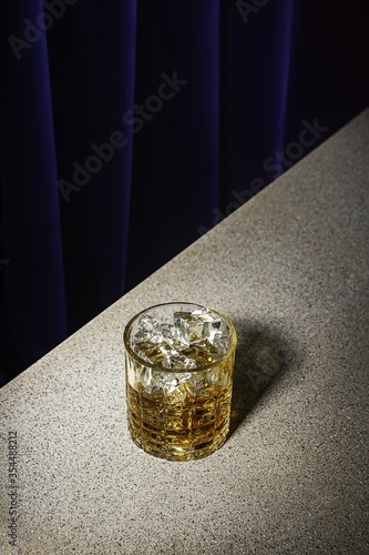 Closeup vertical shot of a glass of wisket with ice on a granite table photo