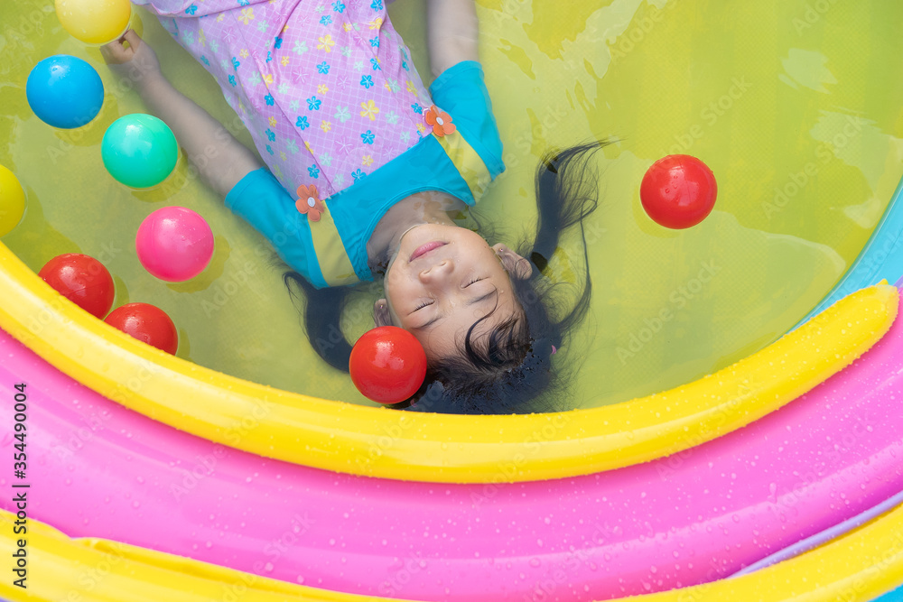 Obraz premium Asian cute girl playing in inflatable baby pool.