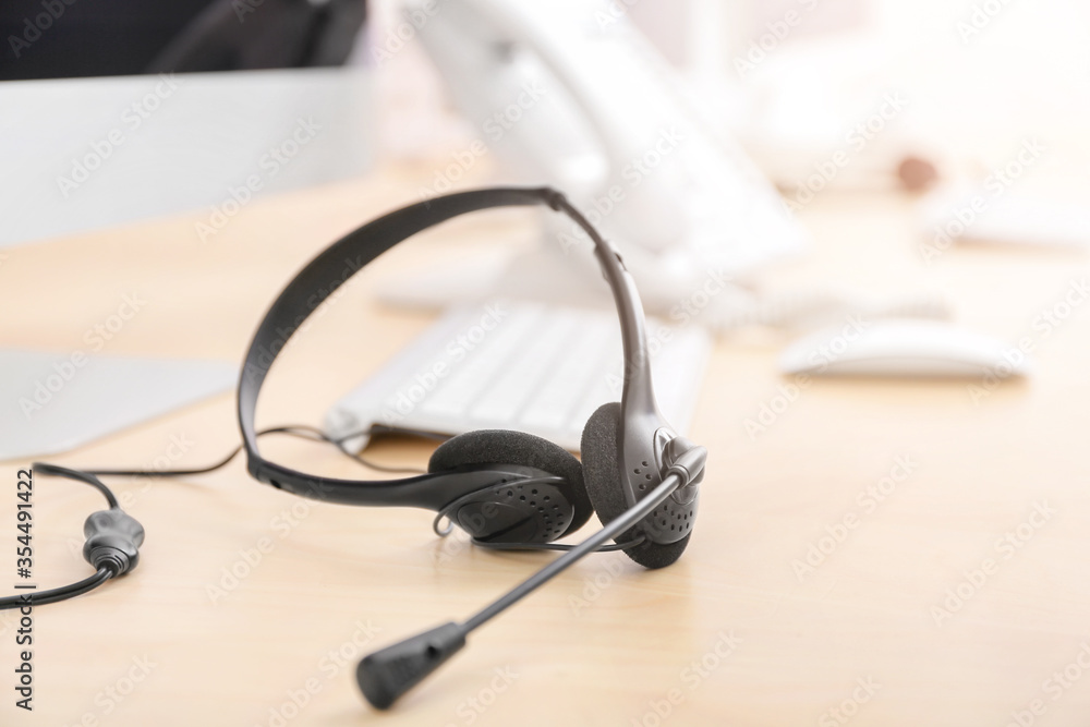 Headset and computer on table of technical support agent in office Headset and computer on table of technical support agent in office