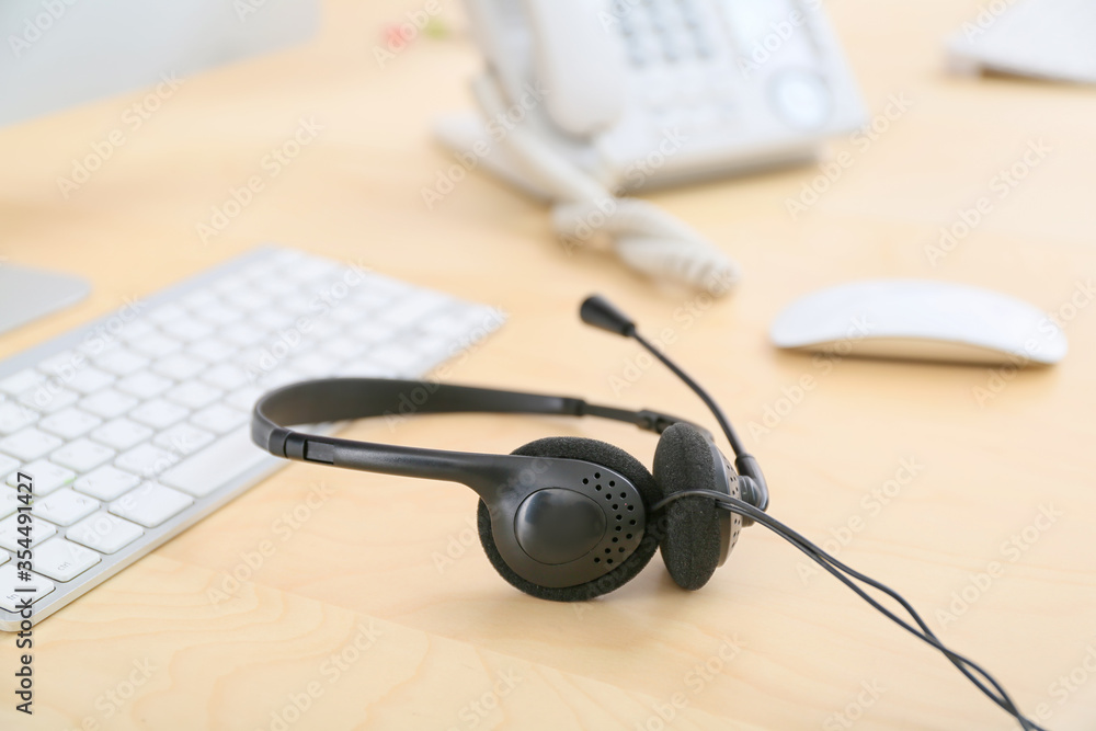 Headset and computer on table of technical support agent in office Headset and computer on table of technical support agent in office