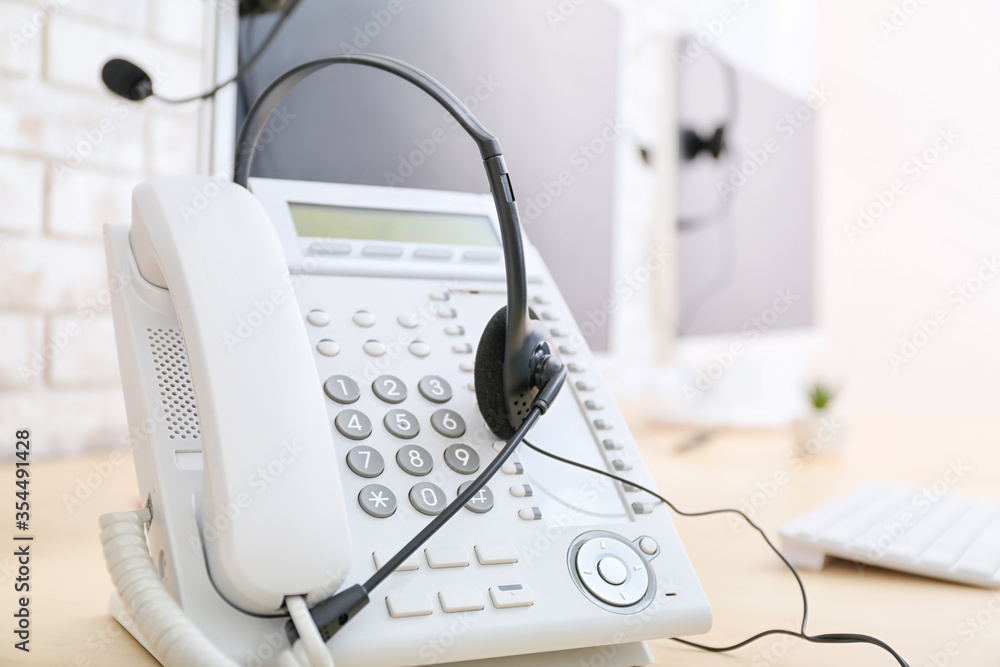 Headset and telephone on table of technical support agent in office