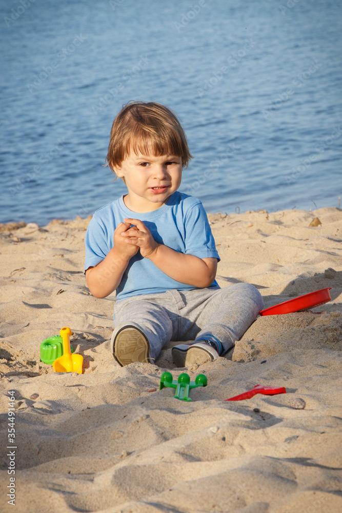 Smiling boy playing on sand at beach. Summer, vacation and relaxation time concept Smiling boy playing on sand at beach. Summer, vacation and relaxation time concept