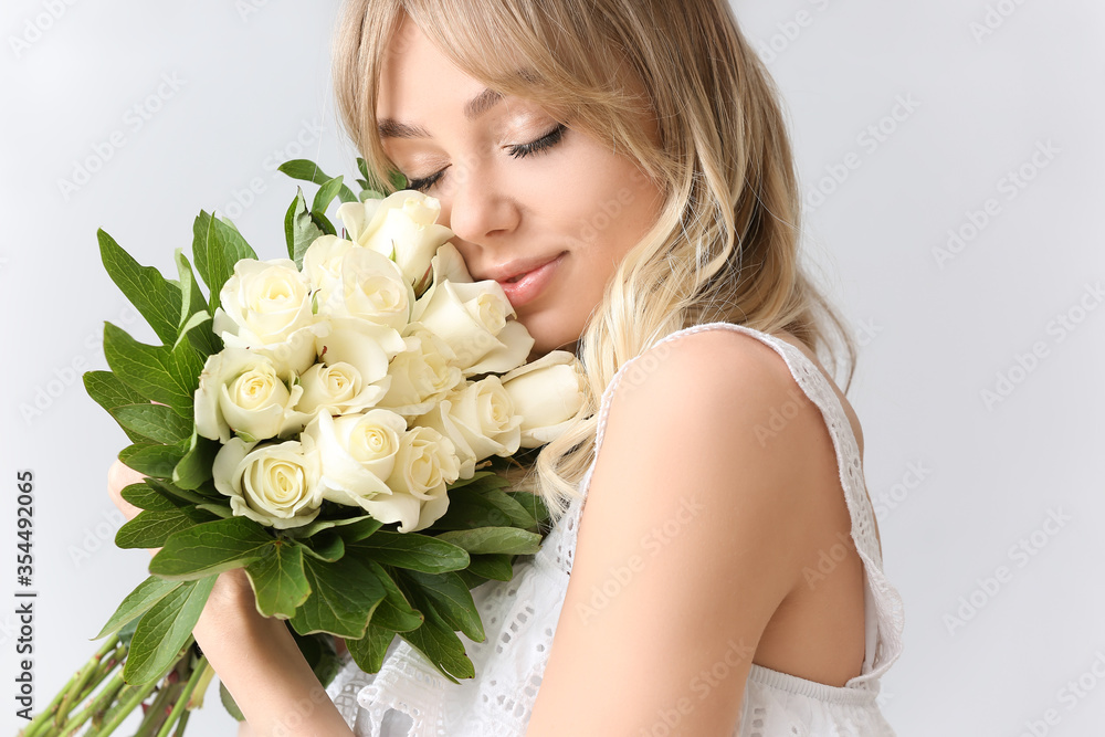 Beautiful young woman with bouquet of roses on light background Beautiful young woman with bouquet of roses on light background
