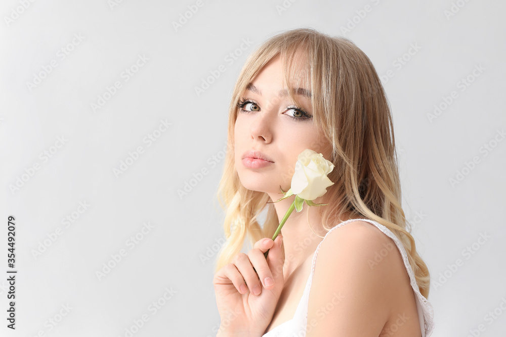 Beautiful young woman with rose on light background Beautiful young woman with rose on light background