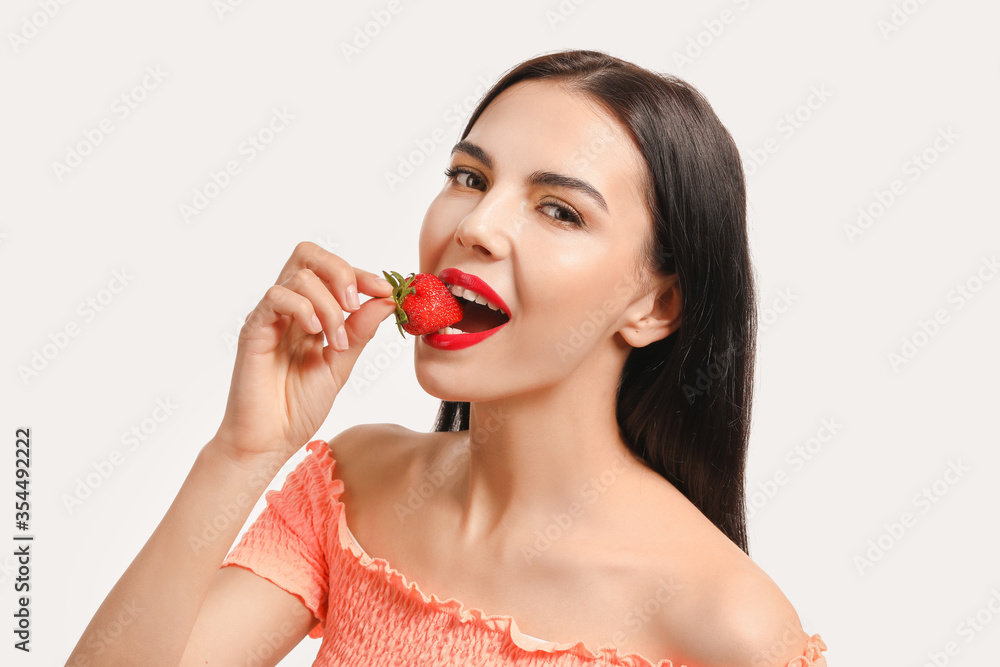 Sexy young woman with strawberry on white background