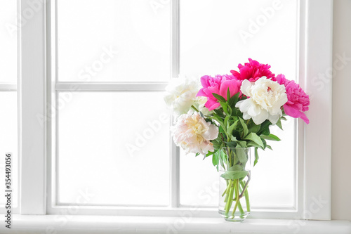 Vase with beautiful peony flowers on window sill