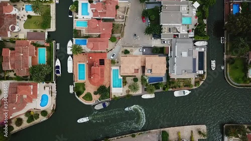 Aerial panning shot of boats in canal amidst buildings in coastal city, drone flying over cityscape - Empuriabrava, Spain photo